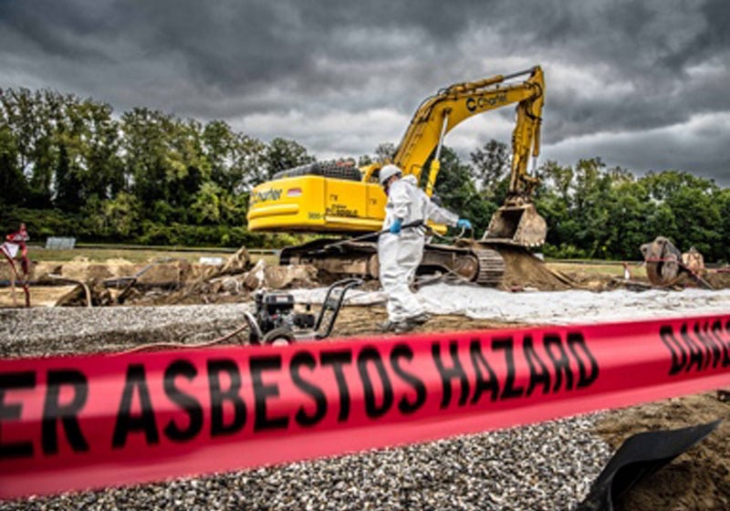 excavator and worker with a close-up of hazard tape