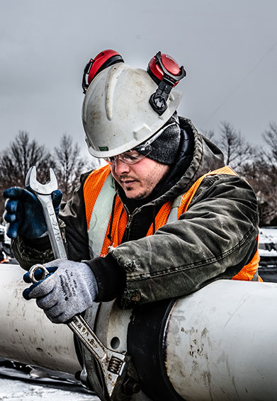 worker tightening pipes with a wrench