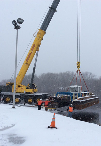 crane lifting up boating equipment from the charles river