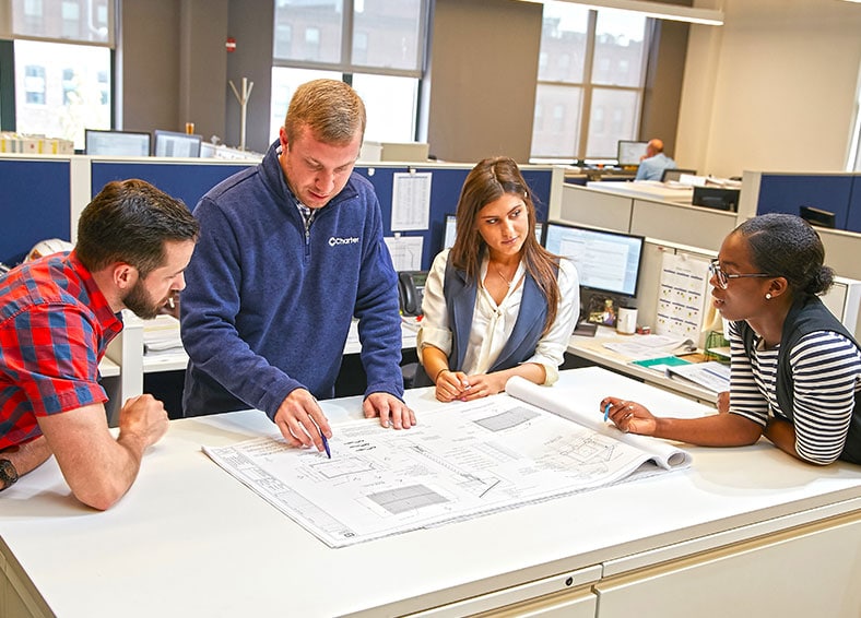 Young project engineers surrounding a blueprint